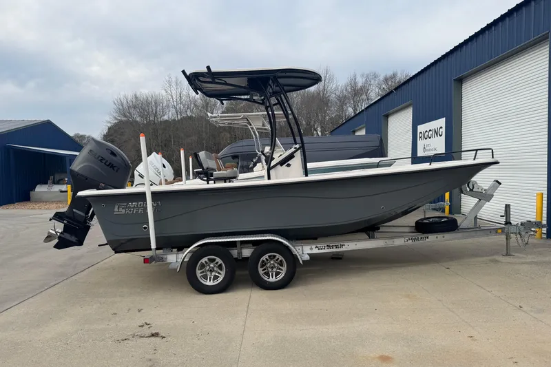 The Image of 2026 Carolina Skiff 21 LS boat on trailer, parked outside a blue building. - 2