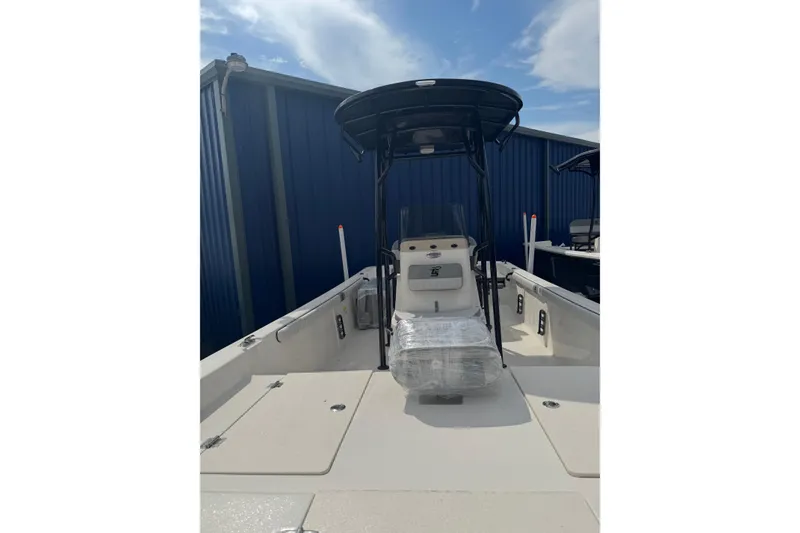 Slide: The Image of 2026 Carolina Skiff 21 LS boat with T-top, docked near blue building. - 3