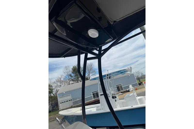 Slide: The Image of 2026 Carolina Skiff 21 LS boat with T-top, parked near a blue building. - 9