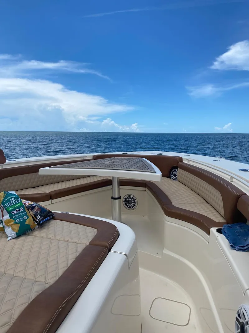 Slide: The Image of 2021 Scout LXF boat interior with ocean view, featuring brown seating and snacks on deck. - 13