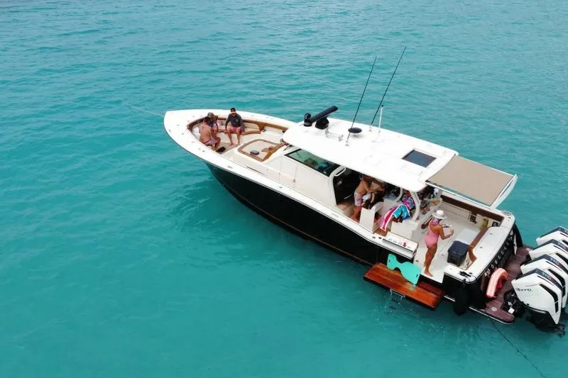 Slide: The Image of 2021 Scout 420 LXF boat on turquoise water with people relaxing onboard. - 3