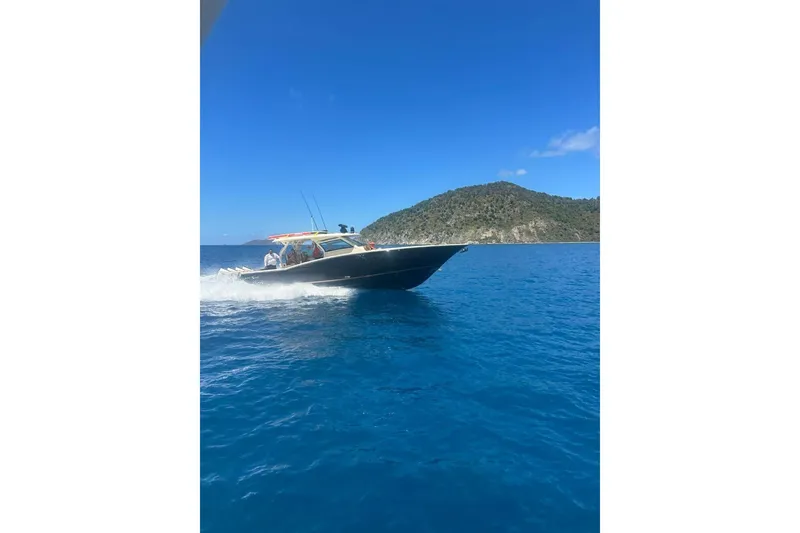 Slide: The Image of 2021 Scout 420 LXF boat cruising on clear blue water near a scenic island. - 4