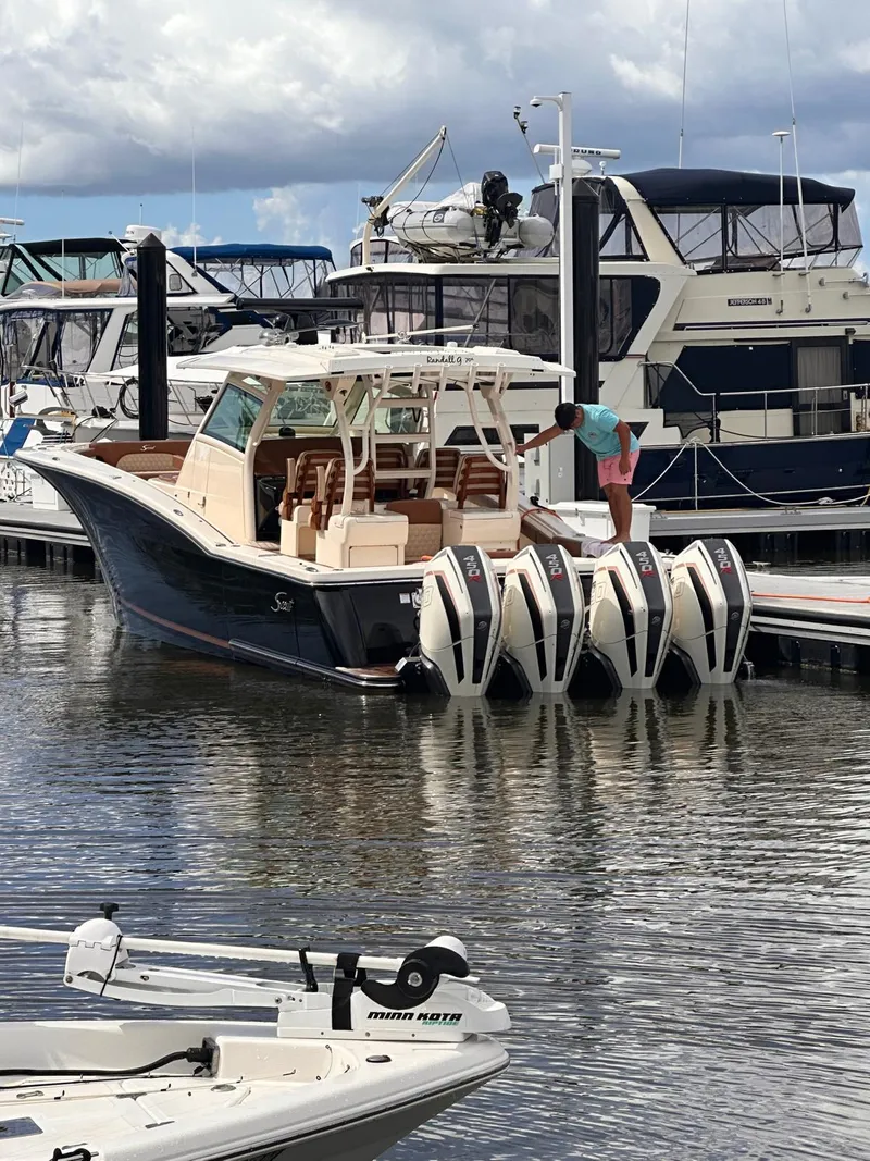 Slide: The Image of 2021 Scout LXF boat docked with four engines, marina background. - 7