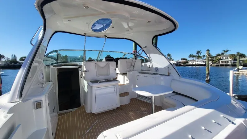 Slide: The Image of 2008 Cruisers 420 Express yacht interior with seating, table, and helm, docked by waterfront homes. - 3