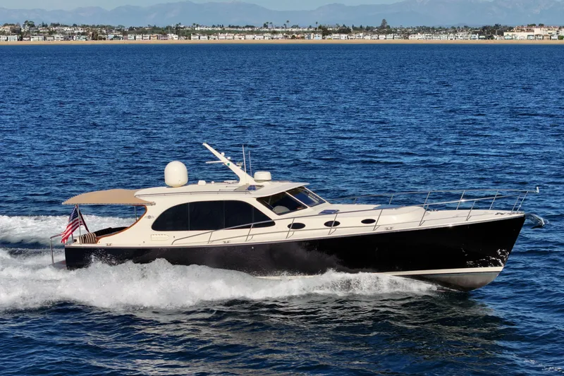 The Image of 2015 Palm Beach Motor Yachts PB45 cruising on open water, coastal background. - 0