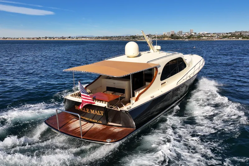 Slide: The Image of 2015 Palm Beach Motor Yachts PB45 cruising on open water, rear view with American flag. - 21
