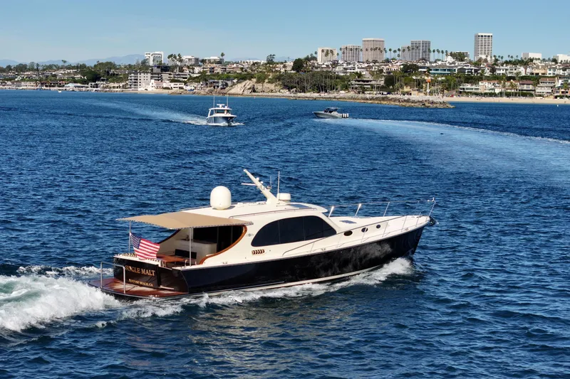 Slide: The Image of 2015 Palm Beach Motor Yachts PB45 cruising near a coastal city skyline. - 22