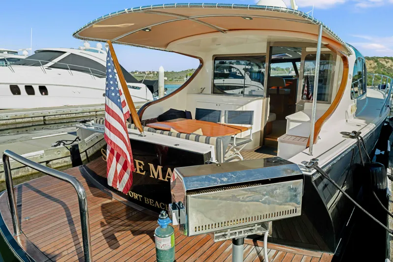 Slide: The Image of 2015 Palm Beach Motor Yachts PB45 docked, featuring a spacious deck and American flag. - 23
