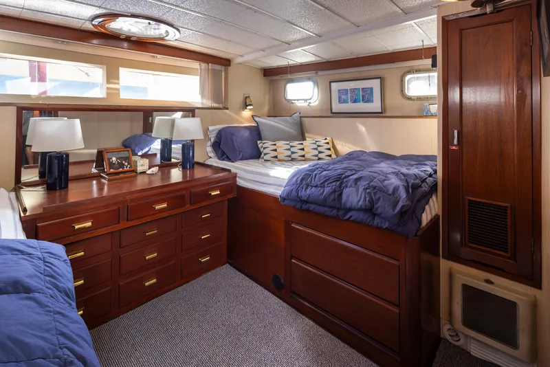 Slide: The Image of Interior of a 1965 Stephens Flushdeck yacht, featuring wooden furniture and cozy bedding. - 27