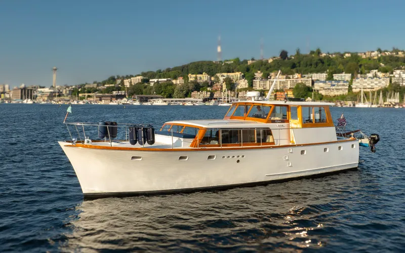 Slide: The Image of 1965 Stephens Flushdeck yacht on calm water with coastal backdrop. - 5