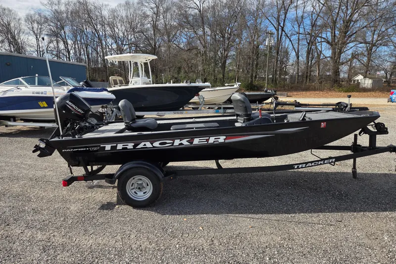 Slide: The Image of 2025 Tracker Panfish 17 boat on trailer, parked outdoors with other boats nearby. - 4