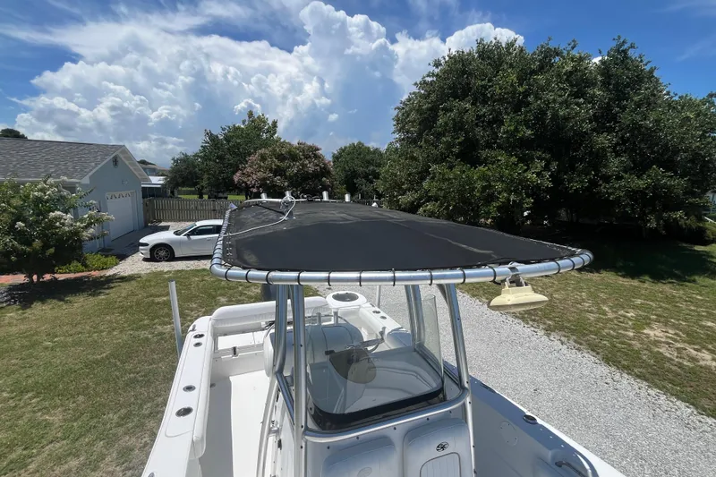 Slide: The Image of 2014 Sea Fox 226 Commander boat with canopy, parked outdoors under a blue sky. - 19