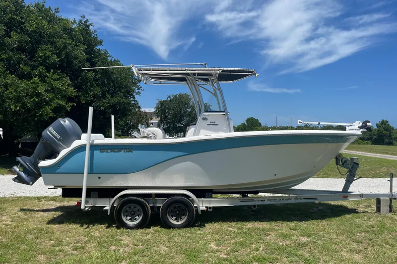Slide: The Image of 2014 Sea Fox 226 Commander boat on trailer, parked on grass under blue sky. - 2