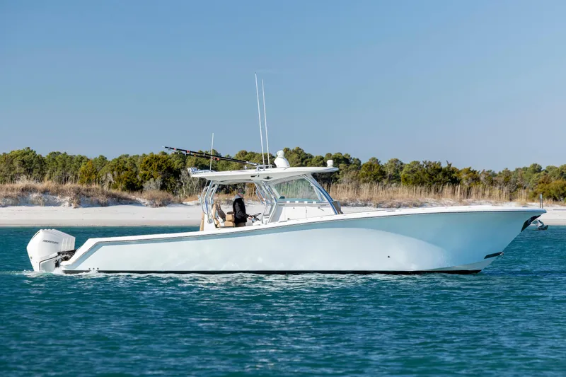 Slide: The Image of 2020 Blackwater 41 Tournament boat cruising near a sandy shoreline with clear blue water. - 0