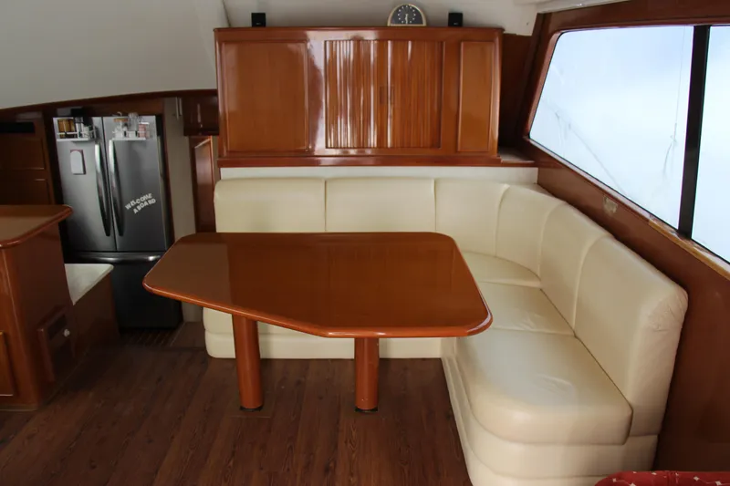 Slide: The Image of Luxurious yacht interior with wooden table, cream leather seating, and modern kitchen appliances. - 6