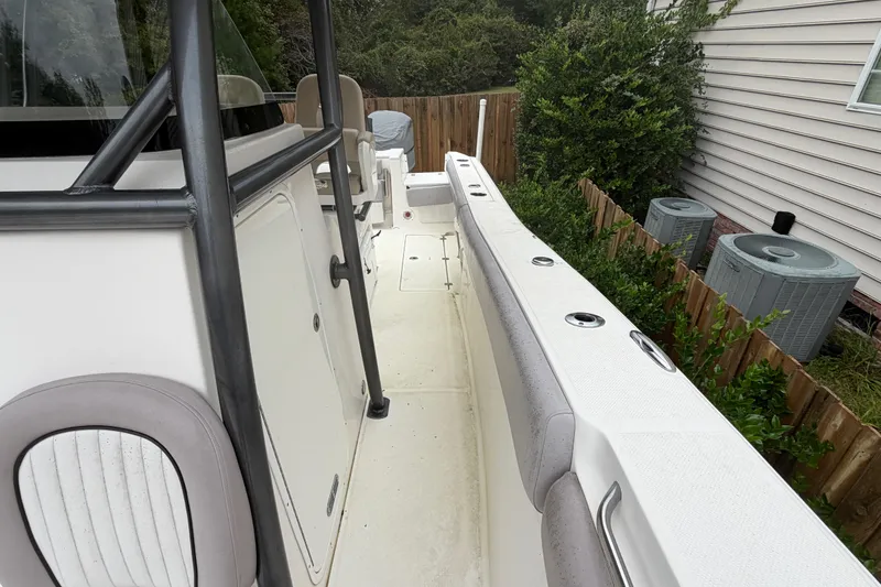 Slide: The Image of 2015 Sea Fox 286 Commander boat interior with seating and railing, parked near a house. - 10