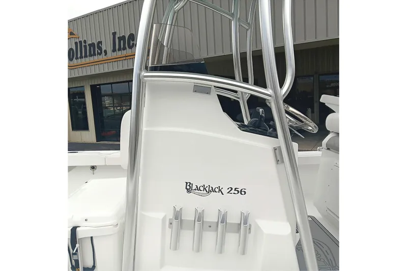 Slide: The Image of 2026 BlackJack 256 Coastal boat console with rod holders, displayed outside a dealership. - 16
