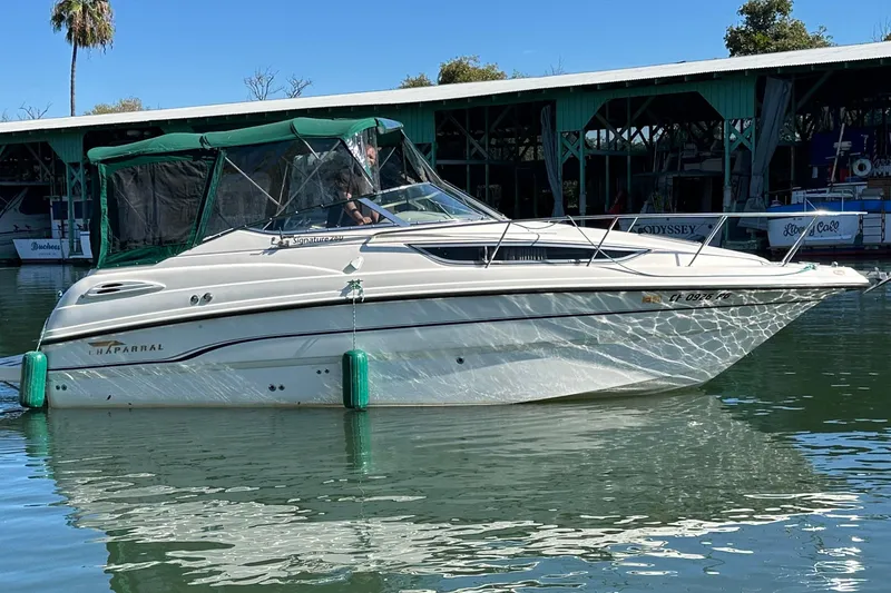 The Image of 1998 Chaparral Signature 2600 boat docked on calm water, with green canopy. - 1