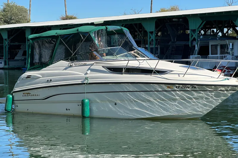 Slide: The Image of 1998 Chaparral Signature 2600 boat docked in marina, green canopy, calm water reflections. - 16