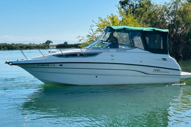 Slide: The Image of 1998 Chaparral Signature 2600 boat on calm water with green canopy. - 17