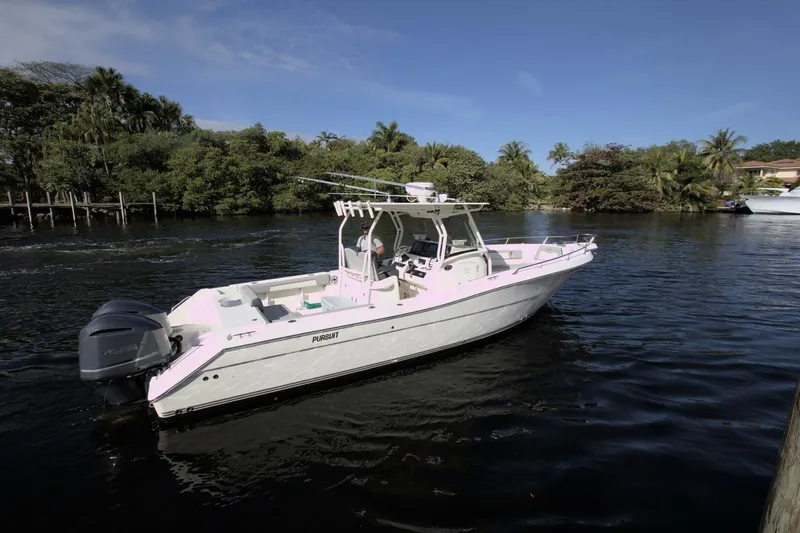Slide: The Image of 2001 Pursuit 3070 Center Console boat on a calm river with lush greenery. - 2