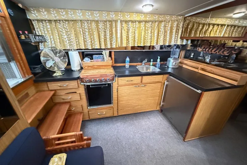 Slide: The Image of 1969 Chris-Craft 338 Commander kitchen with wood cabinetry, stove, sink, and retro decor. - 5