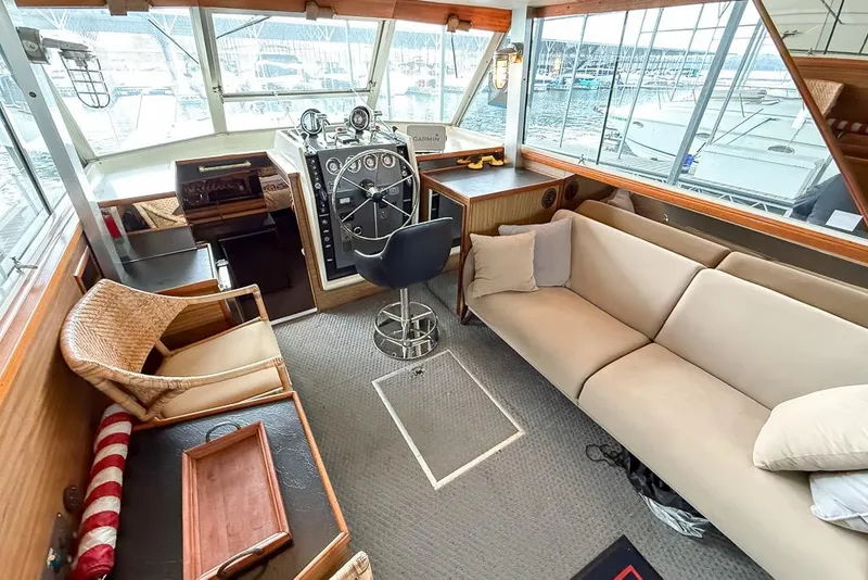 Slide: The Image of 1969 Chris-Craft 338 Commander interior with helm, seating, and large windows overlooking marina. - 2