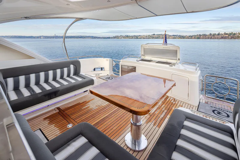 Slide: The Image of 2017 Riviera Sport Cruiser yacht deck with seating and table, overlooking calm waters. - 39