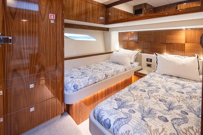 Slide: The Image of 2017 Riviera Sport Cruiser cabin with twin beds, wood paneling, and nautical-themed bedding. - 33