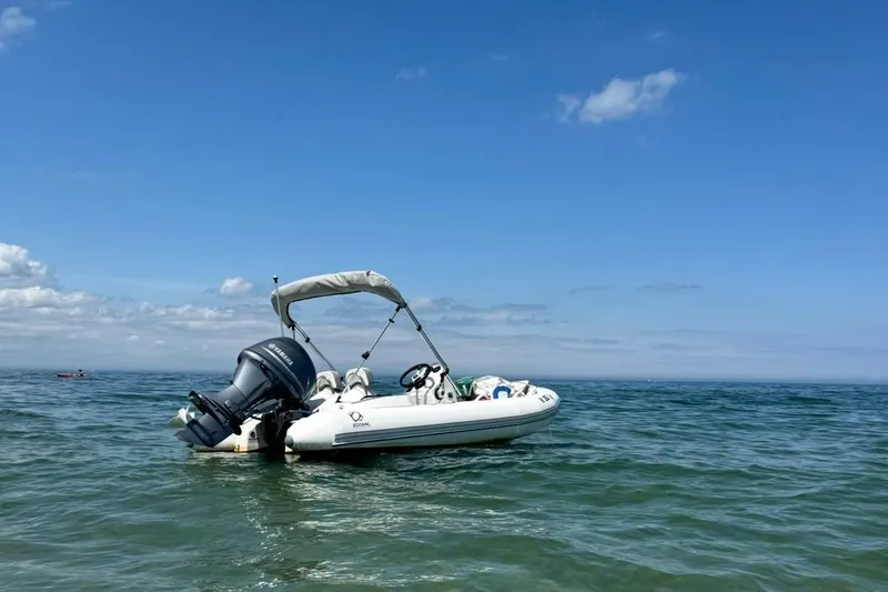 The Image of 2024 Zodiac Yachtline 440 inflatable boat on calm ocean waters under clear blue sky. - 1