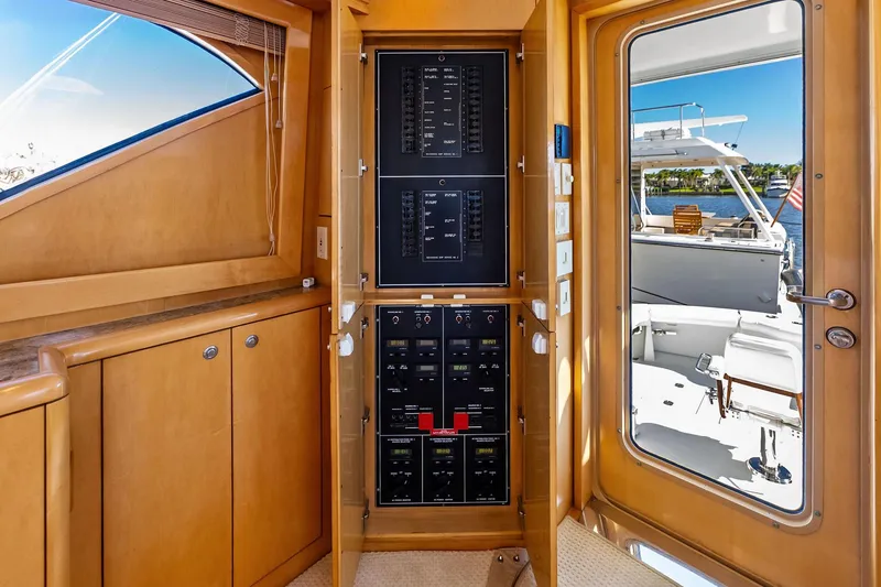 Slide: The Image of Electrical panel inside 2003 Hatteras 65 Convertible yacht, with view of deck and water. - 33