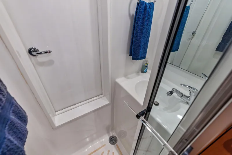 Slide: The Image of Compact bathroom with shower in 2003 Hatteras 65 Convertible yacht, featuring blue towels and modern fixtures. - 61