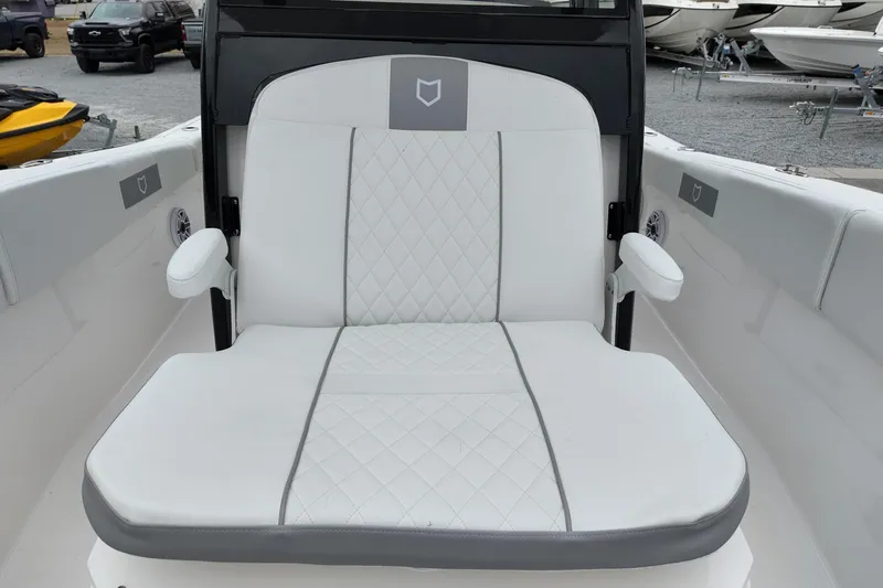 Slide: The Image of 2026 Sea Fox 288 Commander boat seat with white and gray upholstery, docked near other boats. - 8