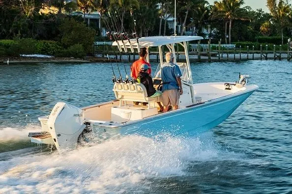 Slide: The Image of Manufacturer Provided Image: 2026 Boston Whaler 210 Montauk boat cruising on water with passengers, palm trees in background. - 2