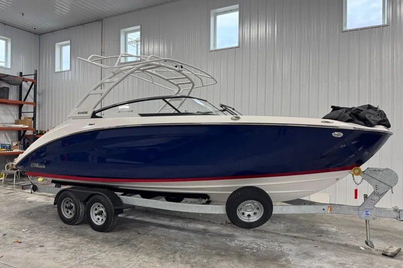 The Image of 2025 Yamaha Boats 252SE in a garage, blue hull, on a trailer. - 0