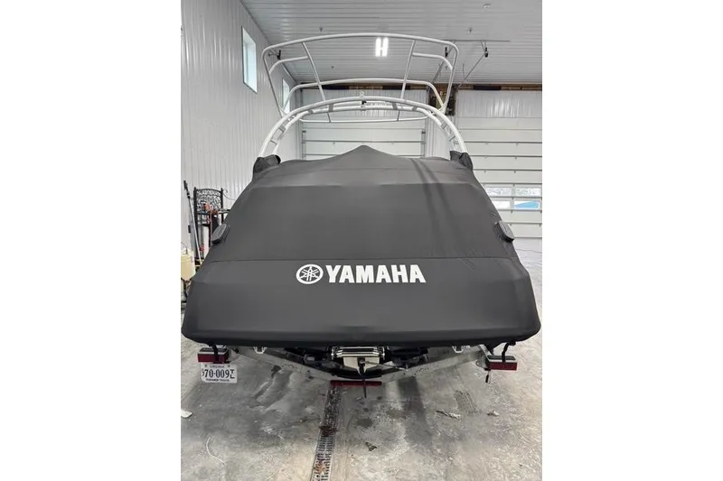 Slide: The Image of 2025 Yamaha Boats 252SE covered in a garage, showcasing rear view and protective cover. - 20
