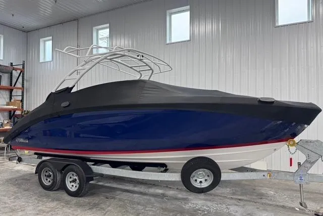 Slide: The Image of 2025 Yamaha Boats 252SE, blue hull, covered, on trailer in indoor storage. - 3