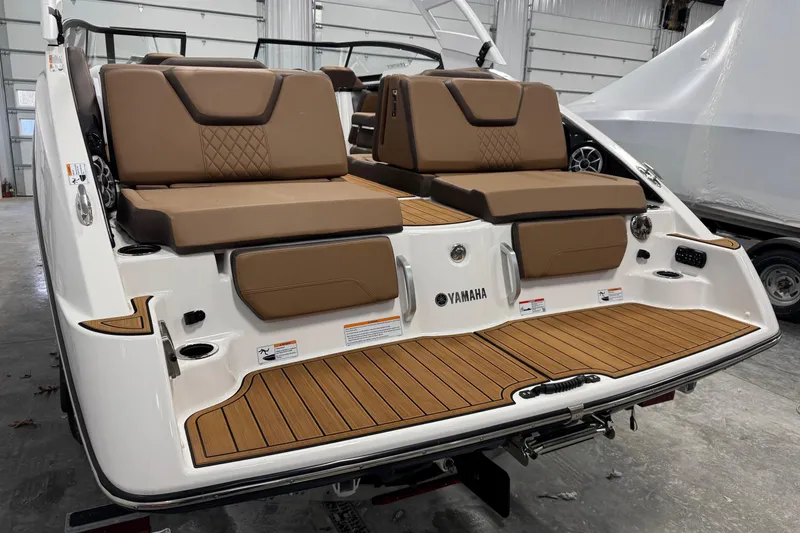Slide: The Image of 2025 Yamaha Boats 252SE with brown seating and teak-style swim platform in a garage. - 5