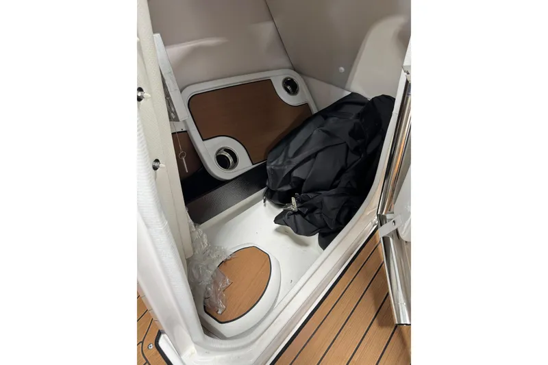 Slide: The Image of 2025 Yamaha Boats 252SE interior storage compartment with wooden accents and black bag. - 7