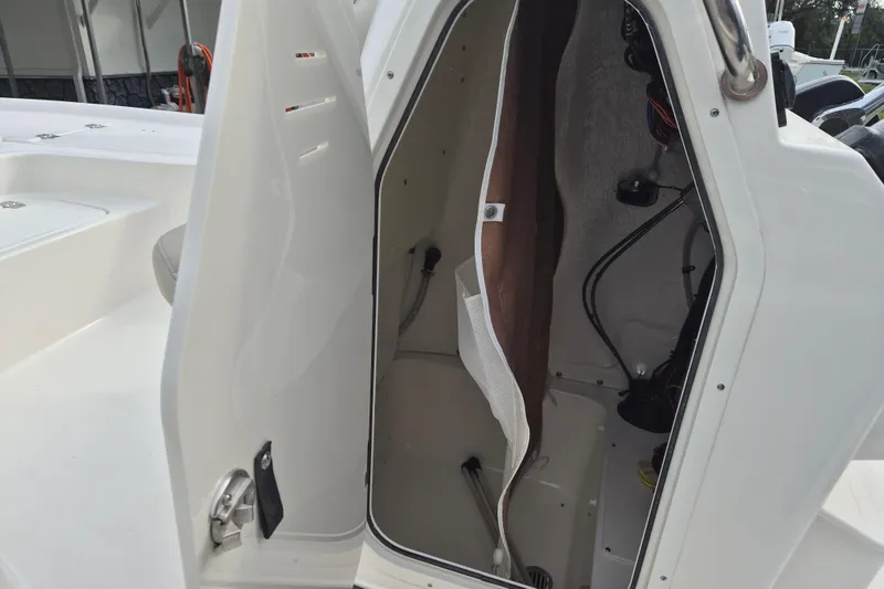 Slide: The Image of 2026 Key West 210 Bay Reef boat storage compartment with open hatch and visible wiring. - 16
