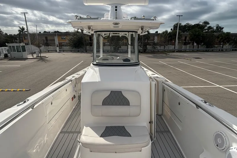 Slide: The Image of 2015 Edgewater 320CC boat interior with seating, parked in an empty lot. - 14