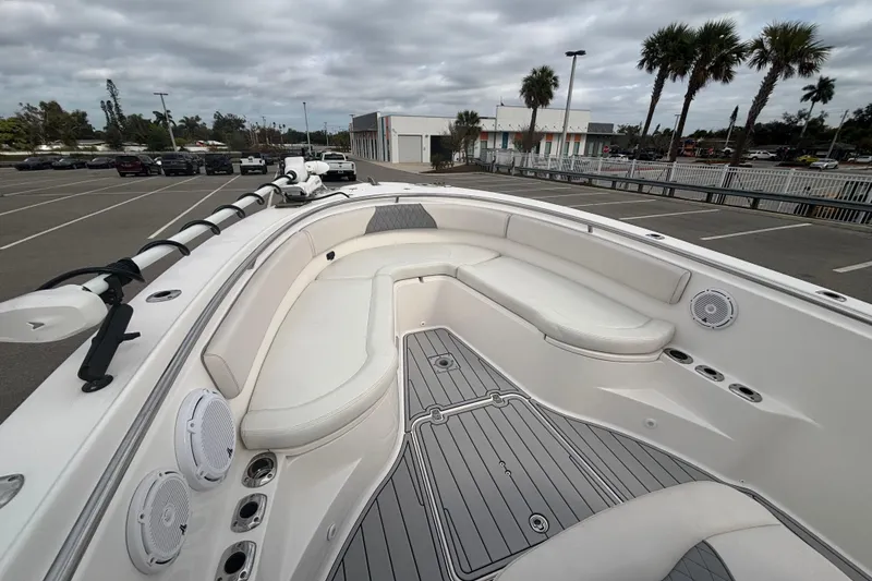 Slide: The Image of 2015 Edgewater 320CC boat interior with white seating and gray flooring in a parking lot. - 18