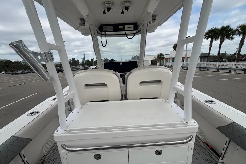 Slide: The Image of 2015 Edgewater 320CC boat interior with seating and console, parked outdoors. - 24