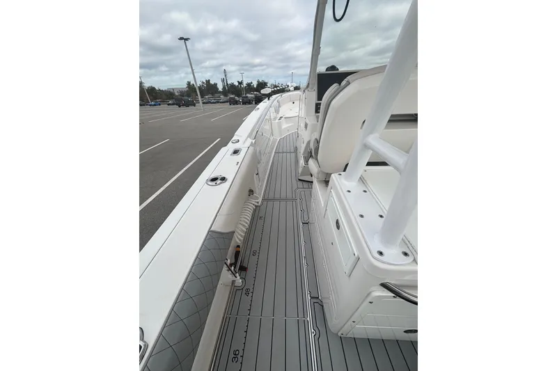 Slide: The Image of 2015 Edgewater 320CC boat interior with sleek deck design in a parking lot setting. - 28