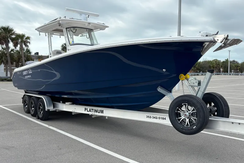 Slide: The Image of 2015 Edgewater 320CC boat on trailer in parking lot, overcast sky. - 7