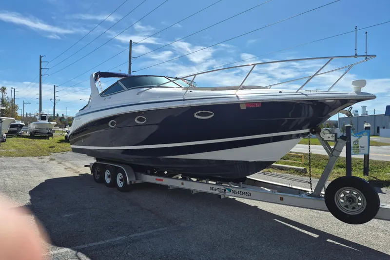 The Image of 2003 Chris-Craft 328 Express Cruiser on trailer under clear blue sky. - 0