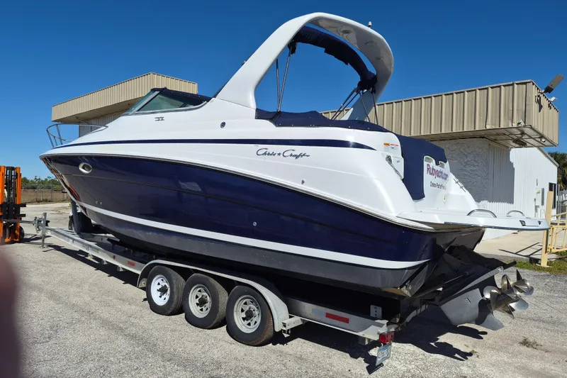 Slide: The Image of 2003 Chris-Craft 328 Express Cruiser on trailer, blue and white design, parked outdoors. - 2