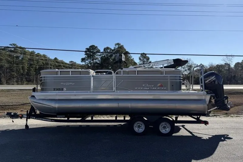 The Image of 2023 Sun Tracker Party Barge 20 DLX pontoon boat on trailer, parked outdoors. - 0