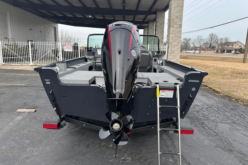 Slide: The Image of 2026 Lund 1775 Adventure Sport boat with outboard motor and ladder, parked outdoors. - 2