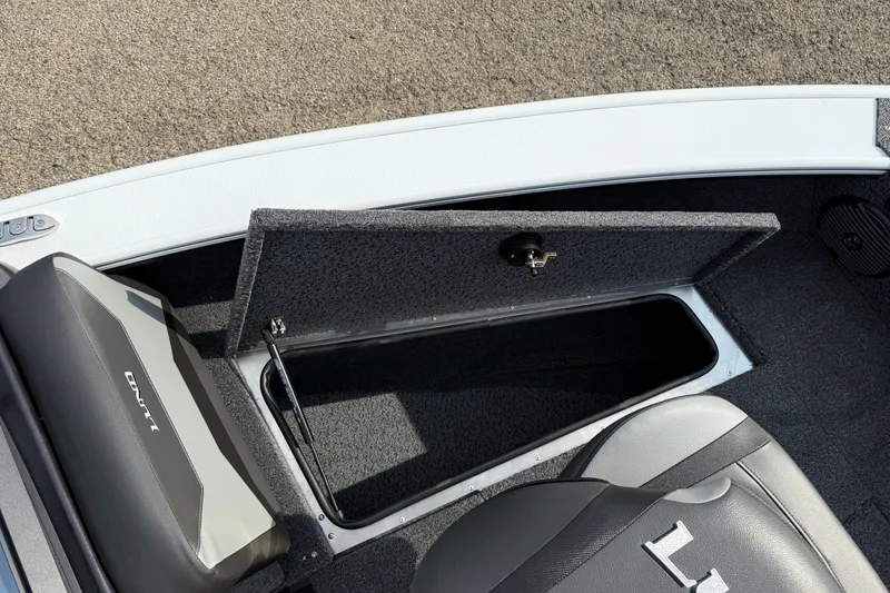 Slide: The Image of 2026 Lund 1875 Crossover XS boat storage compartment with open lid and seating area. - 14